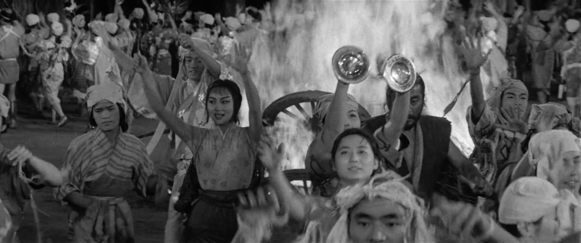 a crowd dancing and singing around a fire